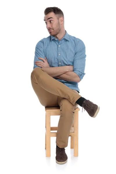 白いスタジオの背景に椅子に座っている間に彼の手を取って交差し 不一致を保持している賢いカジュアルな男を悩ませた — ストック写真