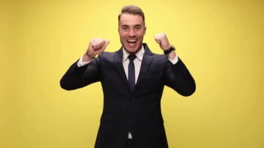 Çekici, heyecanlı iş adamı, iki eli sarı arka planda, tamam işareti yapıyor.