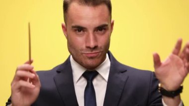 Yüzünde bir gülümsemeyle yöneten bir müzisyen iş adamının yakın çekim görüntüsü. Sonra sarı arka planda daha sert ve tutkulu hale geliyor.