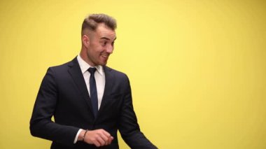 Genç ve seksi iş adamı sürekli bir tarafı işaret ediyor ve sarı arka planda heyecanlanıyor.