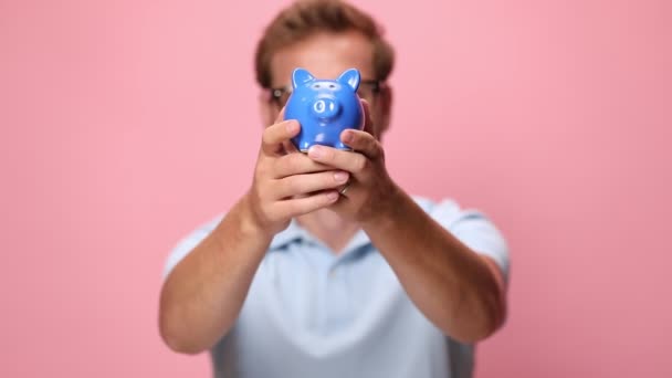 Lässiger Glücklicher Kerl Blauen Poloshirt Mit Sparschwein Vor Dem Gesicht — Stockvideo