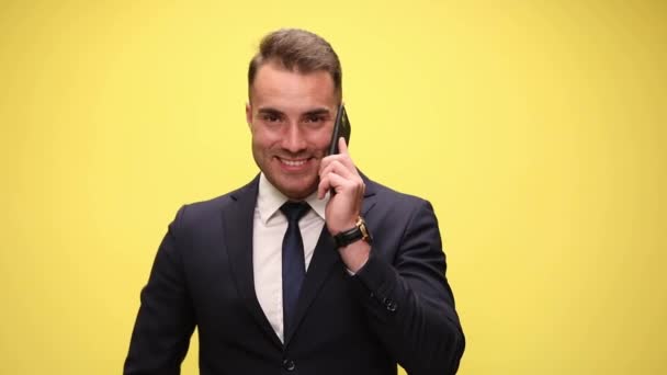 Bonito Empresário Falando Telefone Apontando Para Câmera Sorrindo Fundo Amarelo — Vídeo de Stock