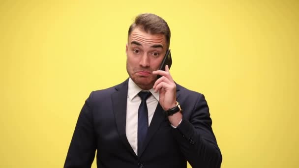 電話で話しているビジネスマンが嬉しそうに笑って黄色の背景に興奮しているのを見て — ストック動画