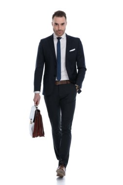 Beyaz stüdyo arka planında el ele yürürken sert bir işadamı evrak çantası tutuyor.