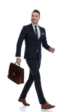 Umutlu iş adamının evrak çantasını tutarken beyaz stüdyo arka planında yürürken yukarı baktığı yan manzara