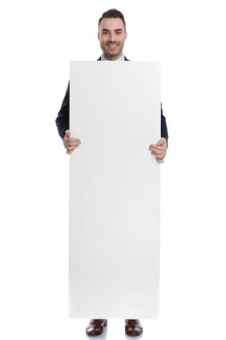 Beyaz stüdyo arka planında dururken vücudunu boş ilan panosuyla kaplayan mutlu iş adamı.