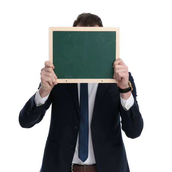 Jungunternehmer Verdeckt Sein Gesicht Mit Tafel Während Auf Weißem Studiohintergrund — Stockfoto