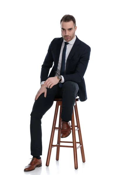 Empresário Duro Inclinado Sua Perna Enquanto Sentado Banquinho Fundo Estúdio — Fotografia de Stock