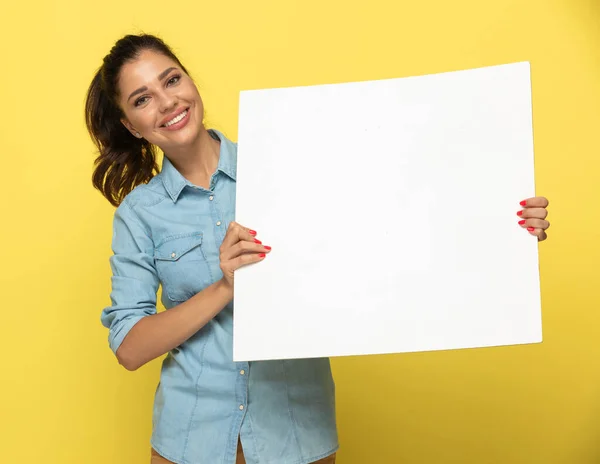 幸せなカジュアル女性笑顔と開催空白の新聞ながら立ち上がっ黄色のスタジオの背景 — ストック写真