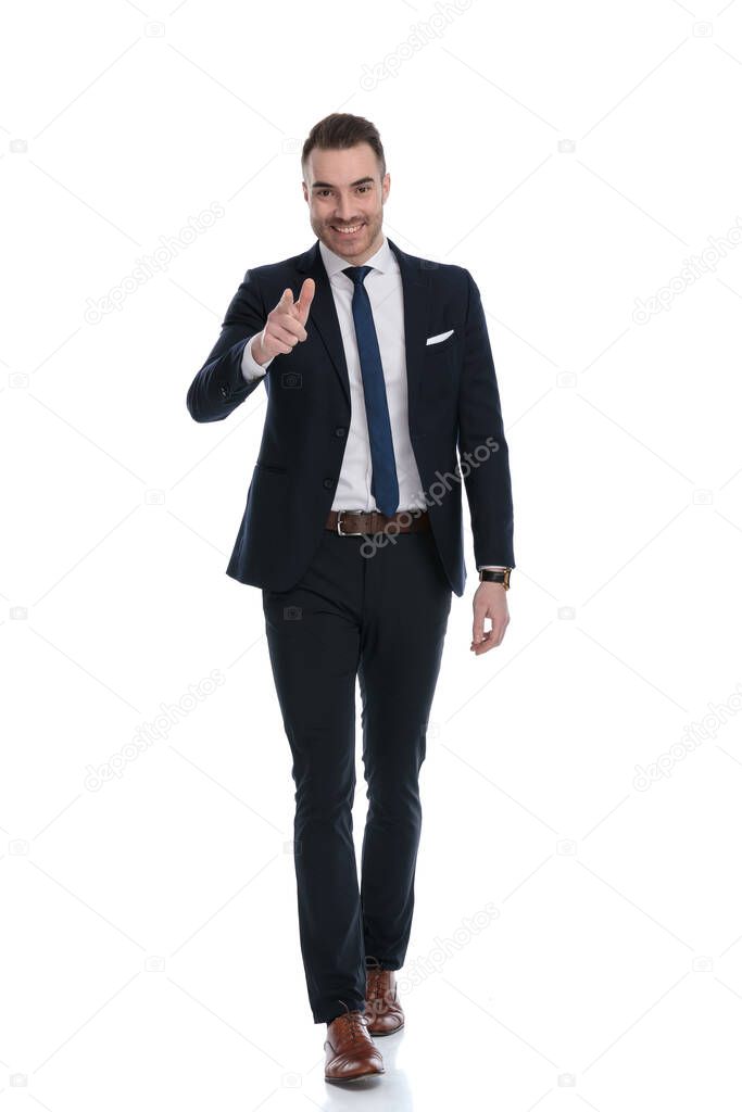 Happy businessman pointing forward and smiling while stepping on white studio background