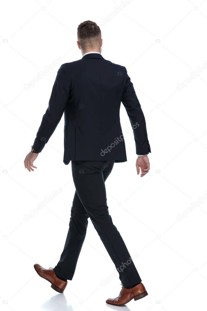 Side rear view of confident wearing suit and walking on white studio background