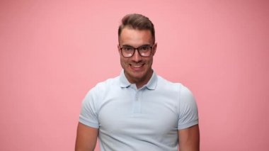 Model gözlük takıyor, gülümsüyor, yumruğunu sallıyor ve pembe arka plandaki başarılarını kutluyor.