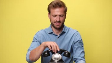 Genç yakışıklı iş adamı telefonda konuşuyor, mutlu bir şekilde şaşırıyor ve sarı arka plandaki başarıları kutluyor.