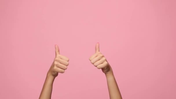 女人的手做着大拇指的姿势 举起拳头庆祝 拍拍粉红的背景 — 图库视频影像