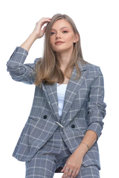幸せな若いビジネス女性で青チェッカースーツアレンジ髪と笑顔 上に隔離された座って白い背景 — ストック写真