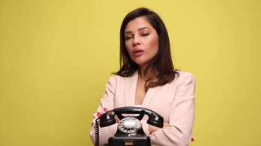 Güzel bir iş kadını eski bir telefonun yanında duruyor ve cevaplamak istiyor ya da istemiyor, telefona cevap veriyor, konuşuyor, hiçbir ipucu bırakmıyor ve kollarını kavuşturuyor.