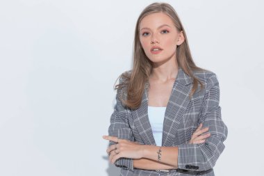 Beyaz stüdyo arka planında dururken el ele tutuşup takım elbise giyen çekici moda işkadını.