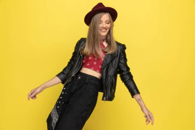 Mutlu model, sarı stüdyo arka planında gülüyor ve dans ediyor.