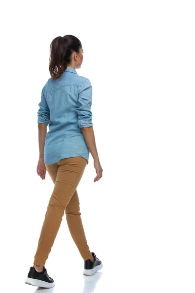 サイドリアビューのスマートカジュアル女性歩行と着てシャツ上のホワイトスタジオ背景 — ストック写真
