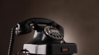 Stüdyoda kahverengi arkaplanda dönen siyah vintage telefon videosu