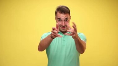 Çekici, sıradan bir adam gülümsüyor, onu ve kamerayı elleriyle gösteriyor ve sarı arka planda ikimizi işaret ediyor.