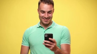 Yakışıklı sıradan bir adam telefonundan e-postalarını okuyor ve sarı arka plan için onay veriyor.