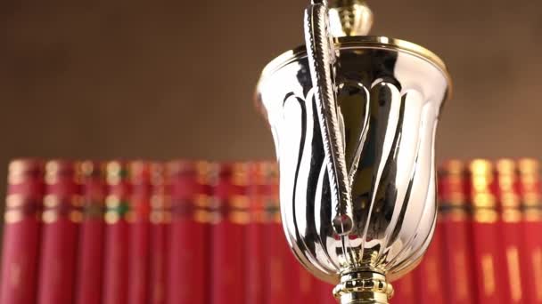 Видео Серебряном Трофее Вращающемся Перед Красными Книгами Фоне Студии — стоковое видео