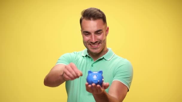 Homem Casual Economizando Seu Dinheiro Banco Porquinho Apontando Para Câmera — Vídeo de Stock