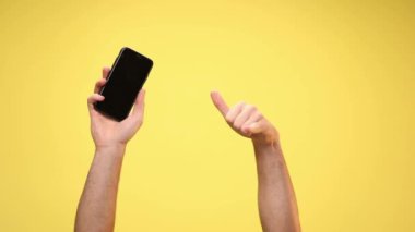 İki kol bir telefon tutuyor ve sarı arka planda beni işaret ediyor.