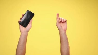 Kamerayı işaret eden iki kol, bir telefon, işaret eden bir işaret işareti ve sarı arka plan.