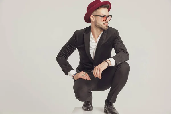 Pensive Fashion Model Looking Away Wearing Sunglasses Hat While Crouching — Stock Photo, Image