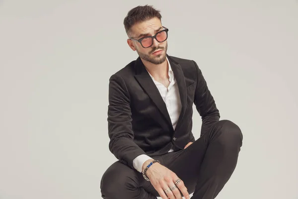 Eager Fashion Model Looking Away Wearing Sunglasses While Crouching Gray — Stock Photo, Image