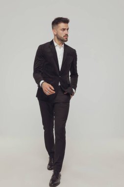 Kendine güveni tam bir manken. Gri stüdyo arka planına adım atarken el ele bakıyor.