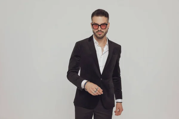 Selbstbewusstes Mode Model Trägt Sonnenbrille Beim Gehen Auf Grauem Studiohintergrund — Stockfoto