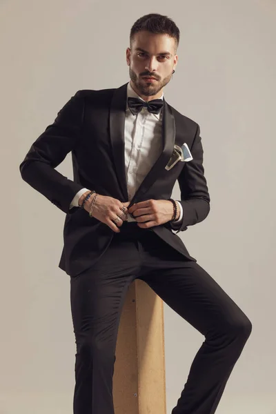 Serious Groom Fixing His Jacket Wearing Tuxedo While Sitting Gray — Stock Photo, Image