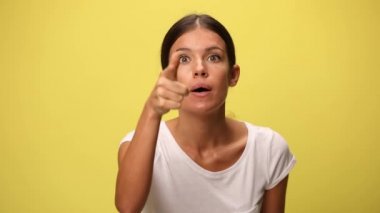 Güzel, sıradan bir kadın, birinin başının etini yiyor, parmağını gösteriyor, yumruğunu gösteriyor ve sarı arka planda umutsuz ve kızgın.