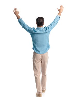 Heyecanlı sıradan bir adamın kollarını başının üstünde tutması ve beyaz arka planda yürürken zaferi kutlaması.