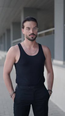 Gözlüklü genç adam ileriye bakıyor ve el ele tutuşuyor, yan yana bakıyor, avuçlarını ovuyor ve arkasına bakmadan yürüyor.