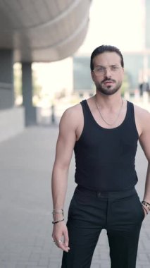 Gözlüklü yakışıklı genç adam el ele tutuşuyor, avuçlarını ovuyor, etrafa bakıyor ve havalı davranıyor.