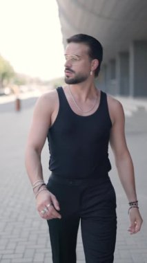 Gözlüklü, yana bakan, yürüyen ve avuçlarını ovuşturan seksi genç adamın dikey videosu.