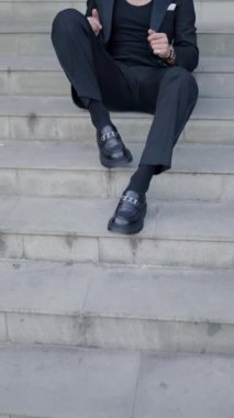 Gözlüklü, ceketini tamir eden havalı moda adamı, Romanya 'dan gelen bir şehirde dirseğiyle merdivenlerde oturmaya çalışıyor, Sibiu.