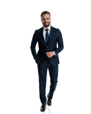 Donanma mavisi takım elbiseli mutlu, zarif bir adamın tüm vücudu cepleri dolu ve beyaz arka planda gülümsüyor.