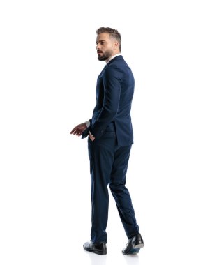 Lacivert takım elbiseli çekici olgun bir adam el ele yürüyor, başka tarafa bakıyor ve beyaz arka planda poz veriyor.
