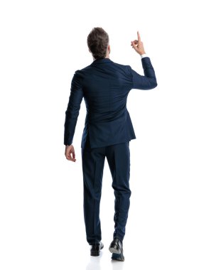 Lacivert takımlı zarif bir adamın dikiz aynasından gökyüzünü gösteren ve beyaz arka planda yürüyen