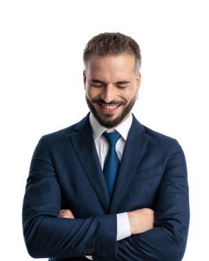 Lacivert takım elbiseli komik olgun bir adamın portresi. Kollarını kavuşturup beyaz arka planda durup gülerken.