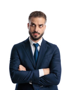 Lacivert takım elbiseli zarif bir işadamının portresi kollarını kavuşturup beyaz arka planda dikilirken merak ediyor.