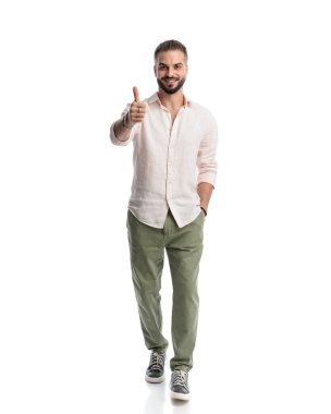 Mutlu genç adam işaret veriyor, gülümsüyor ve beyaz arka planda el ele yürüyor.