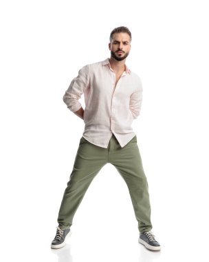 Yakışıklı sakallı adam arkada el ele tutuşuyor ve beyaz arka planda kendine güvenen bir şekilde poz veriyor.