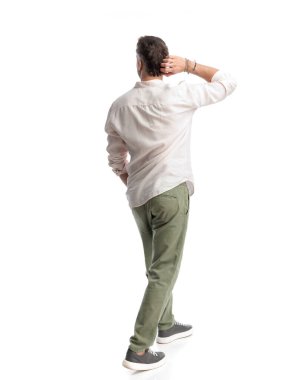 Kafası karışmış genç bir adam beyaz arka planda yürürken düşünüyor.