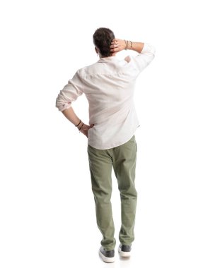 Düşünceli genç adam beyaz arka planda dururken kafasını kaşıyor ve düşünüyor.